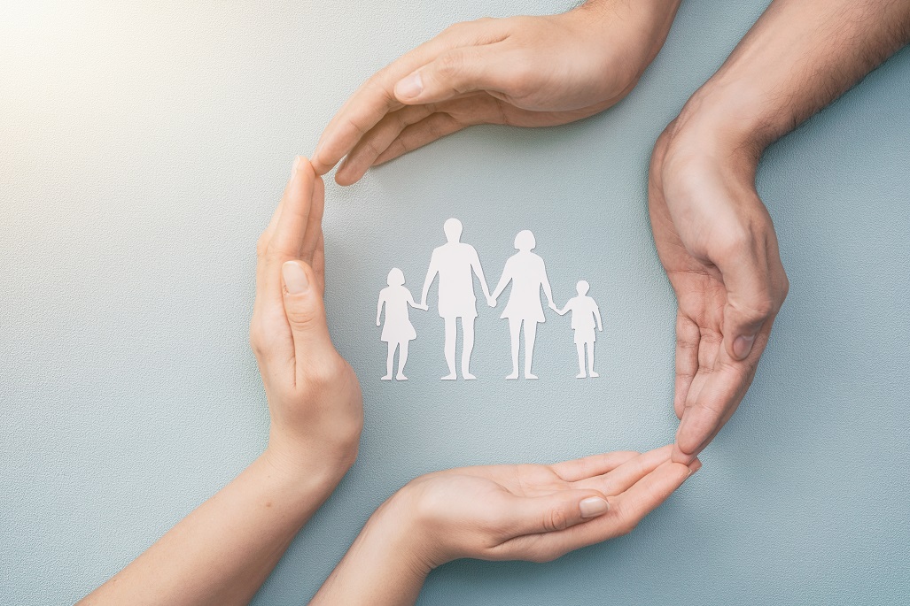Hands with cut out paper silhouette on table. Family care concept.