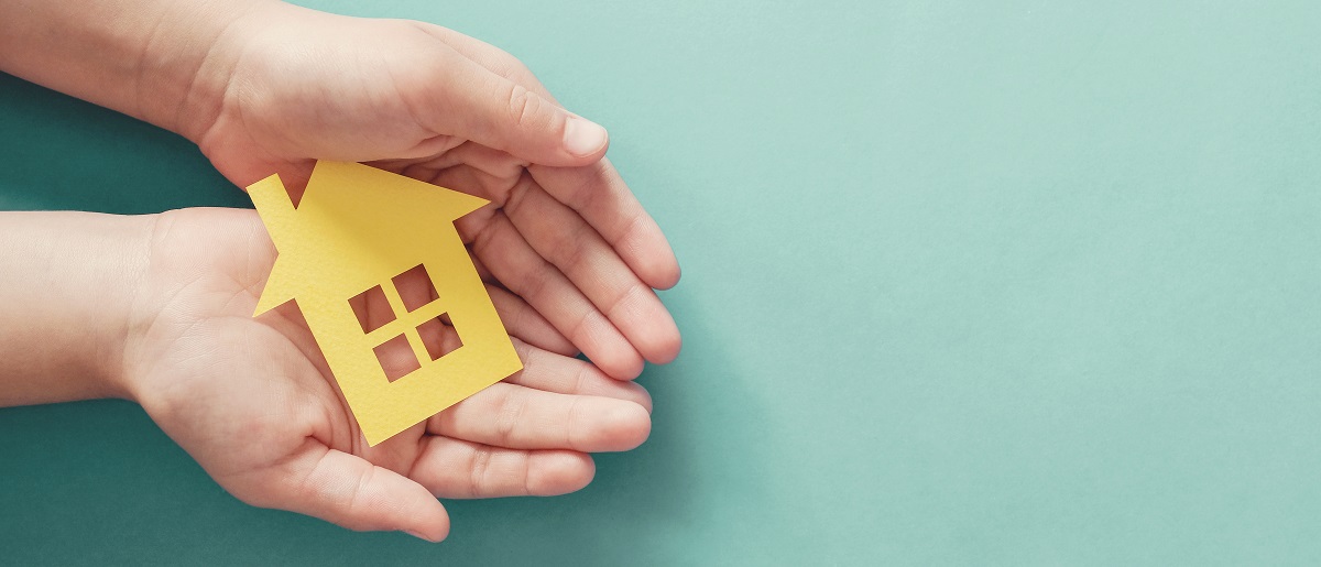 hands holding paper house, family home, homeless housing and home protecting insurance concept, international day of families, foster home care, homeschooling, social distancing